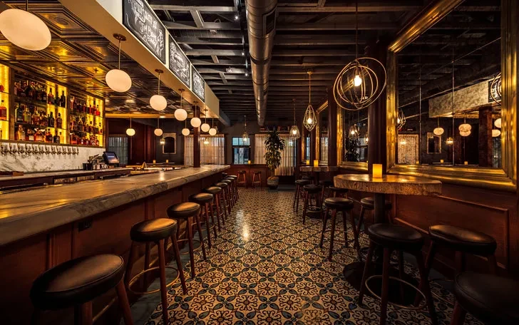 Upscale bar interior with long counter, seating, and ornate tile floor.