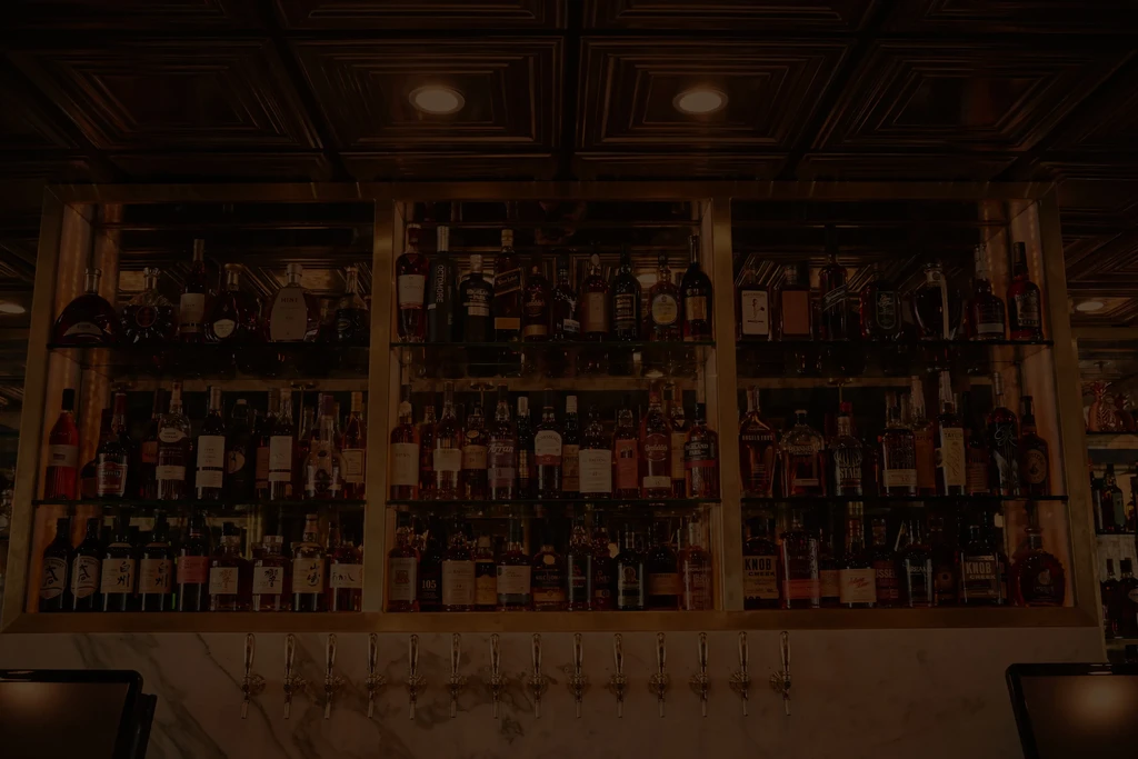 Well-stocked bar with illuminated shelves of bottles and beer taps.