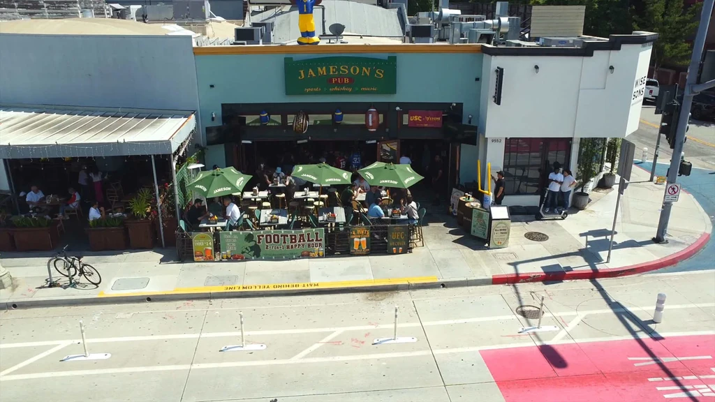 Drone view of Jameson's Pub with a bustling outdoor patio and people.