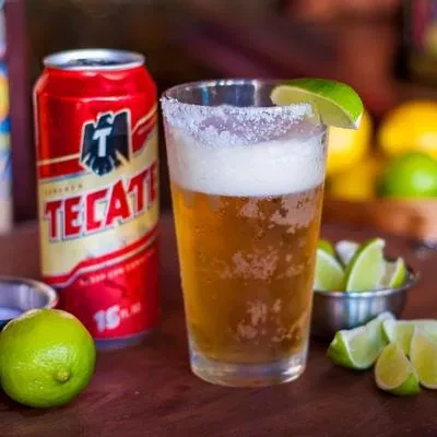 Red Tecate can, salted beer with lime, and fresh limes.