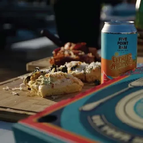 Flatbreads, stew, and 'Citrus Aftermath' beer can on rustic wood.