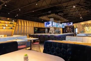 Empty modern restaurant interior with varied seating and a brightly lit bar.