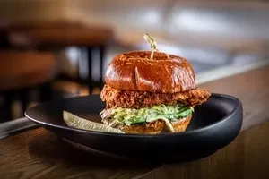 Crispy fried chicken sandwich on brioche bun with coleslaw and pickle.