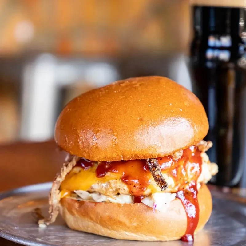 Brioche burger with chicken or fish, melted cheese, and sauce.