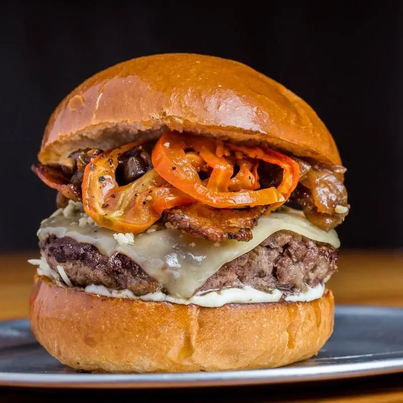 Close-up gourmet burger: brioche bun, beef patty, melted cheese, caramelized onions.