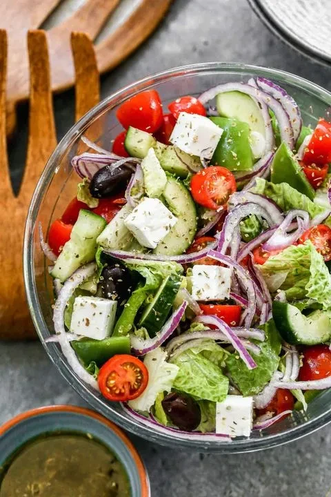 Fresh Greek salad in a glass bowl with feta and olives.