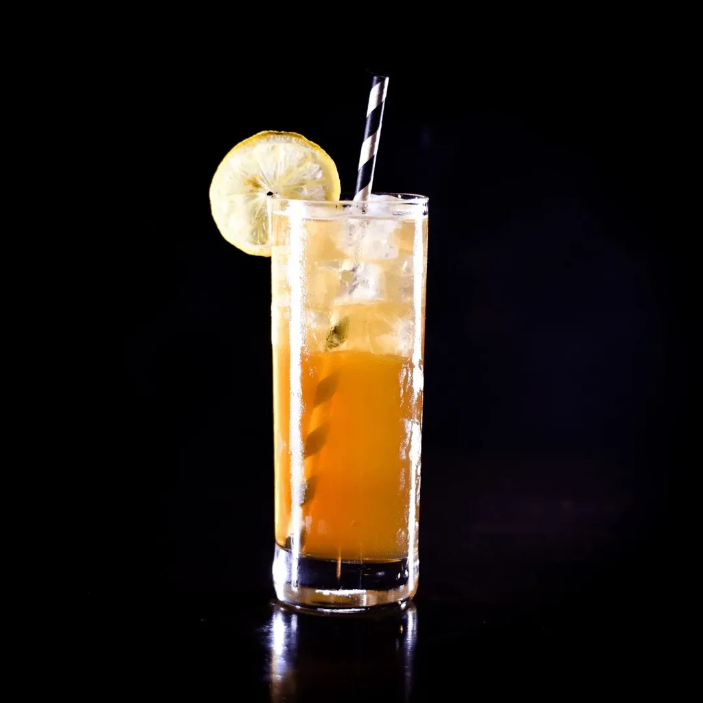 Amber iced drink with mint, lemon slice, and striped straw.