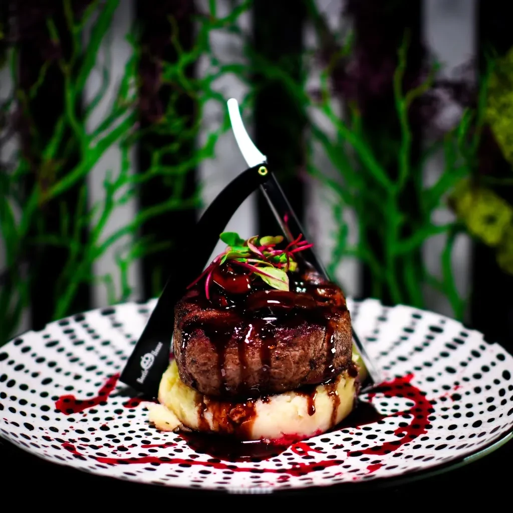Steak with a straight razor garnish on a polka dot plate.