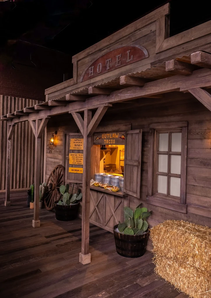 Rustic Western Outlaw Tacos stall with menu and HOTEL sign.