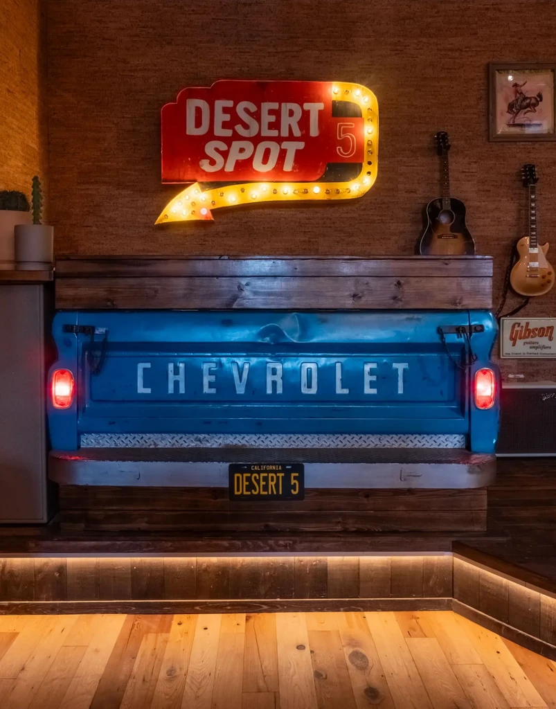 Vintage blue Chevy tailgate bar under a 'DESERT SPOT 5' neon sign.