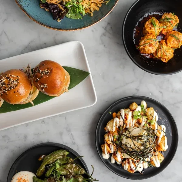 Overhead shot of five diverse dishes on a marble table.