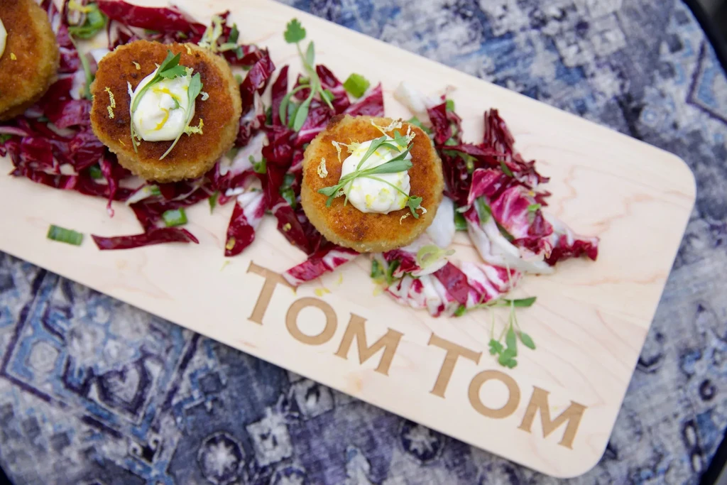 Three fried fritters on a TOM TOM wooden board with radicchio.