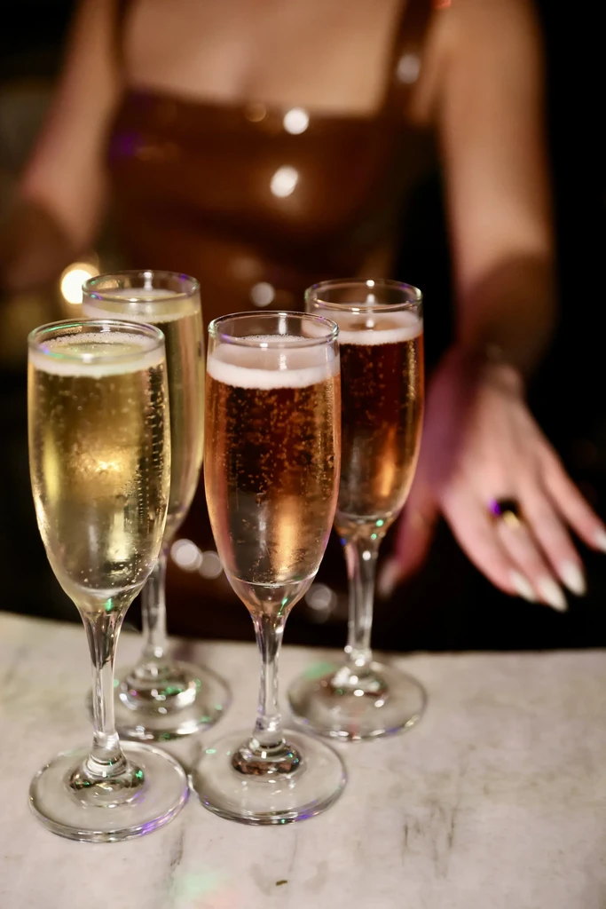 Four bubbly flutes of sparkling wine, two golden and two rosé.