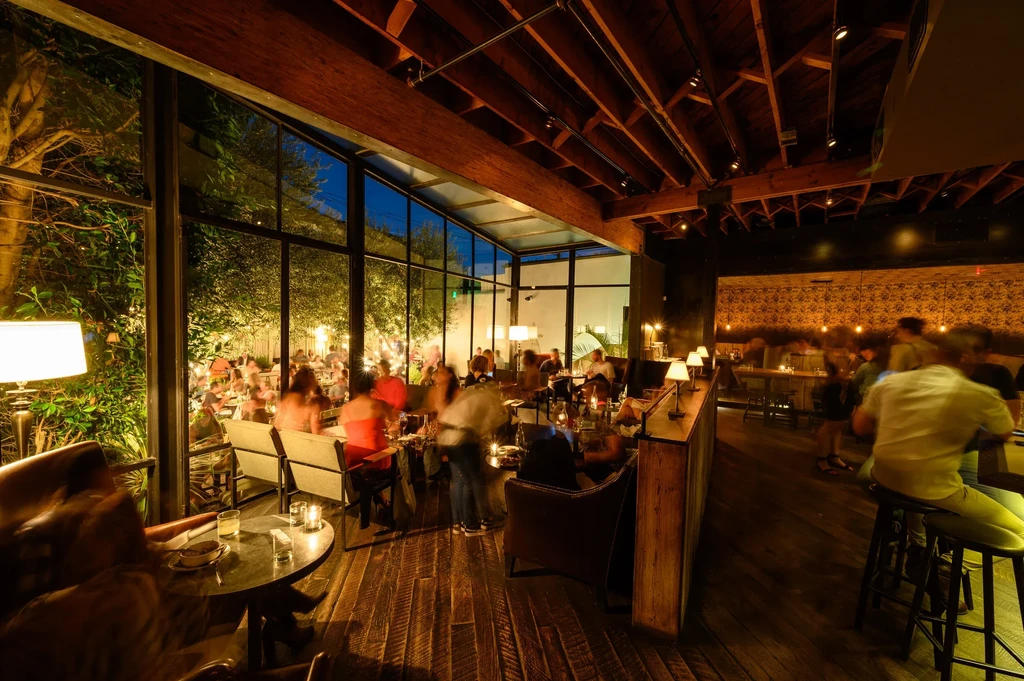 Bustling restaurant at night with warm indoor and lit outdoor dining.