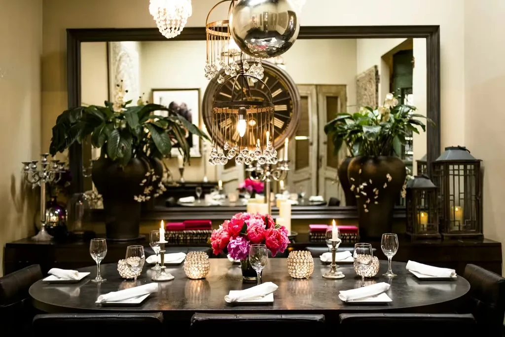 Elegant dining room: oval table with flowers, lit candles, and mirror.