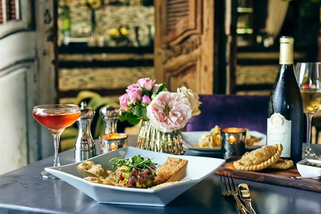 Upscale restaurant table: tuna tartare, empanadas, cocktail, white wine.