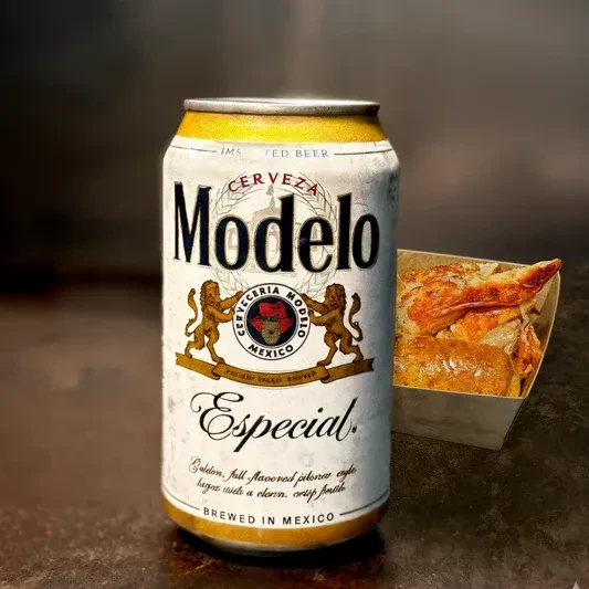 Chilled Modelo Especial beer can and a container of fried food.