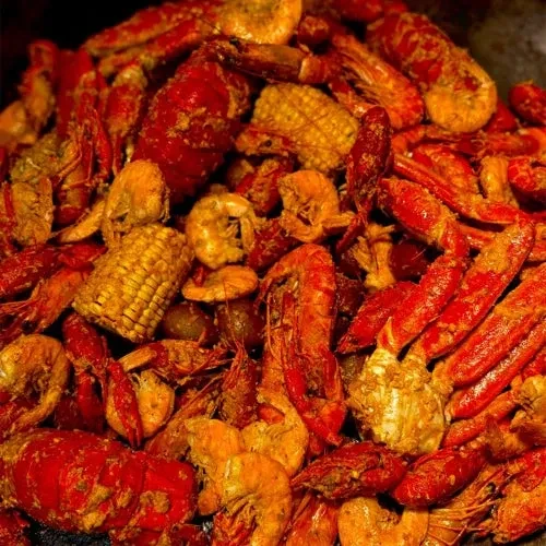 Close-up of a seasoned seafood boil with crawfish, shrimp, and corn.