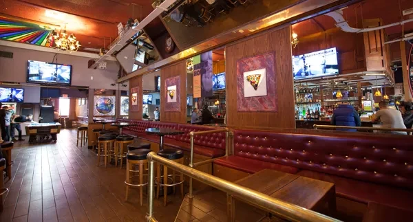 Lively bar interior with red booths, long bar, pool table, and TVs.