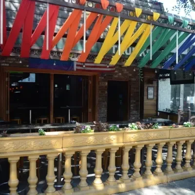 Restaurant exterior with rainbow awning, yellow railing, and open doors.