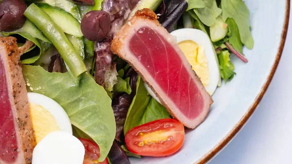 Vibrant seared tuna salad with hard-boiled eggs, olives, and mixed greens.