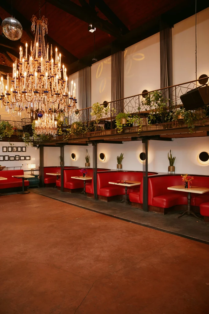 Elegant venue with crystal chandelier, disco ball, mezzanine, and red booths.
