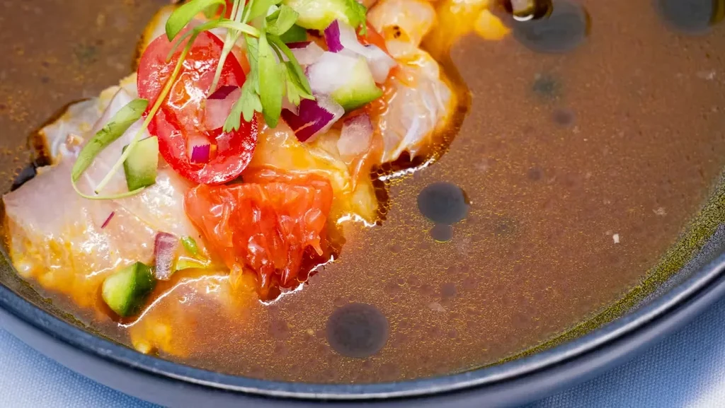 Overhead ceviche with fish, red onions, cucumbers, tomatoes, herbs.