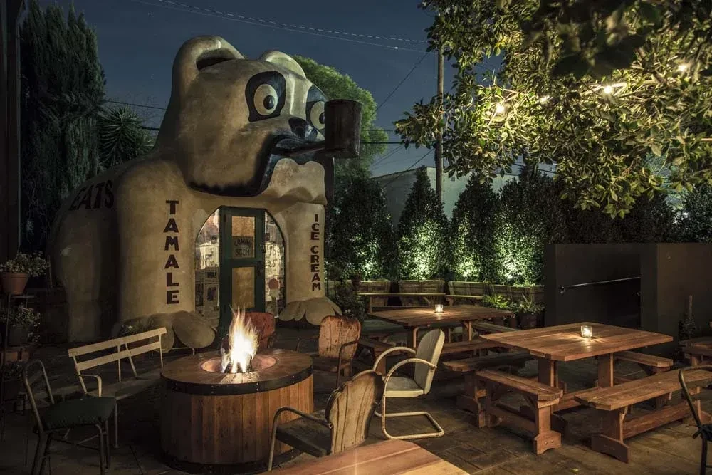 Bear-shaped building entrance reads "TAMALE ICE CREAM" at a cozy night patio.