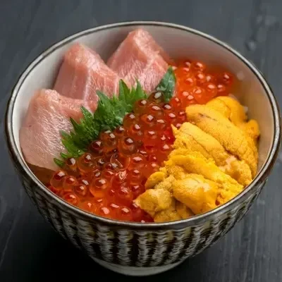 Close-up of a vibrant Japanese donburi with tuna, ikura, and uni.