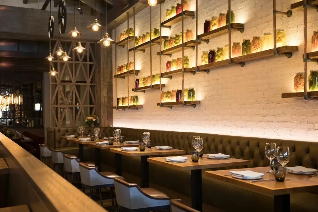 Restaurant interior: white brick, shelves of jarred foods, dark green banquette.
