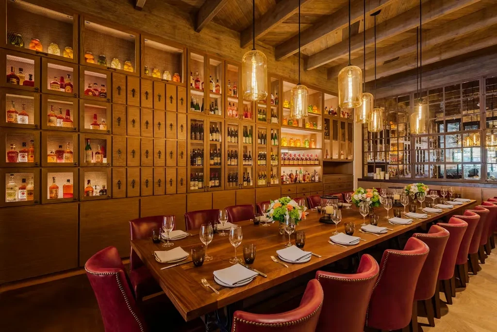 Elegant private dining room with a set table and illuminated bar display.