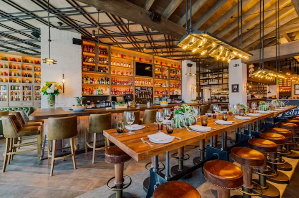 Rustic-industrial restaurant interior with a communal wooden table and liquor bar.