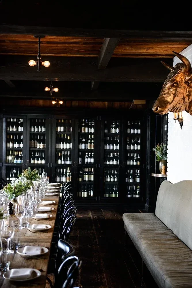 Interior view of upscale restaurant with rustic table, wine wall, bull head.