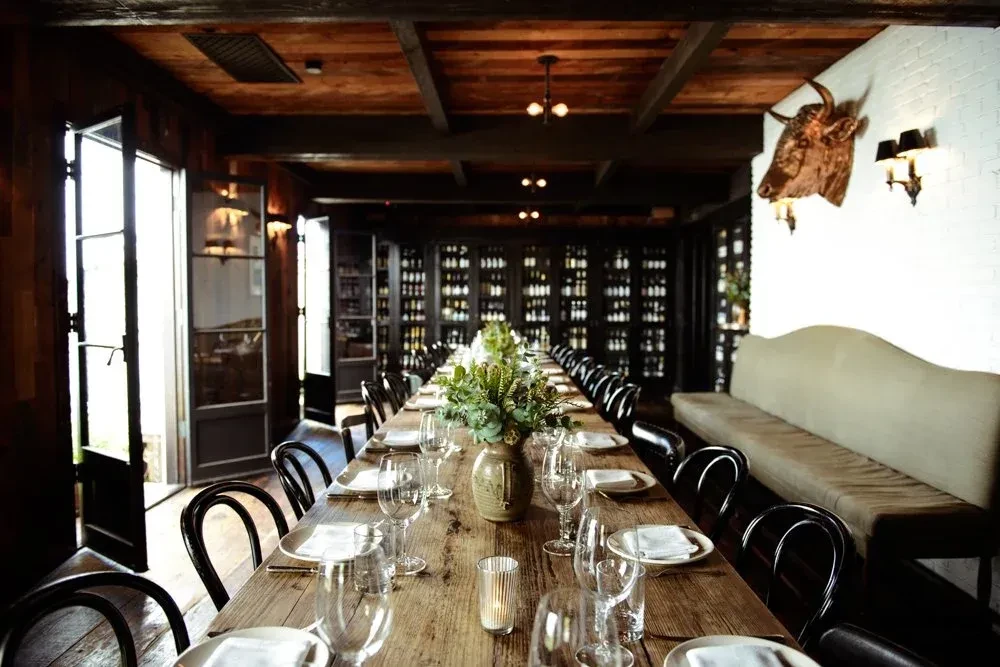Elegant rustic dining room with long set table and wine storage.