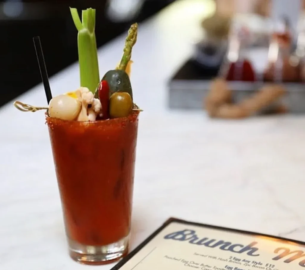 Bloody Mary cocktail with many skewered vegetables and a seasoned rim.