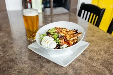 Grilled chicken Cobb salad and a beer on a restaurant table.
