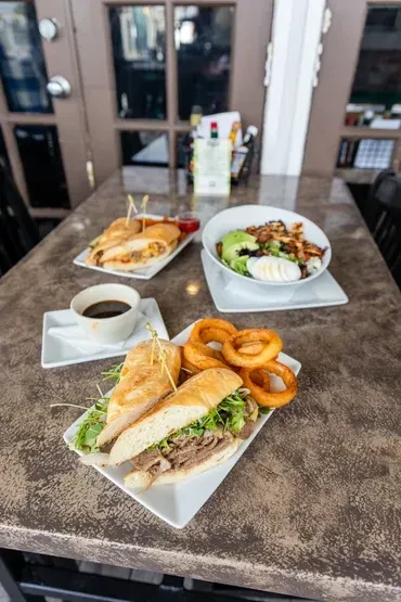 Restaurant table with large sandwich, onion rings, salad, and coffee.