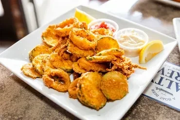 Fried seafood and zucchini platter with sauces and lemon.