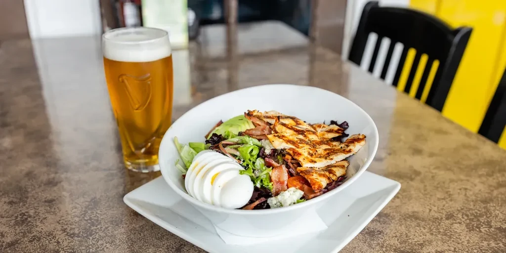 Fresh grilled chicken salad with egg, avocado, bacon, and a Guinness.