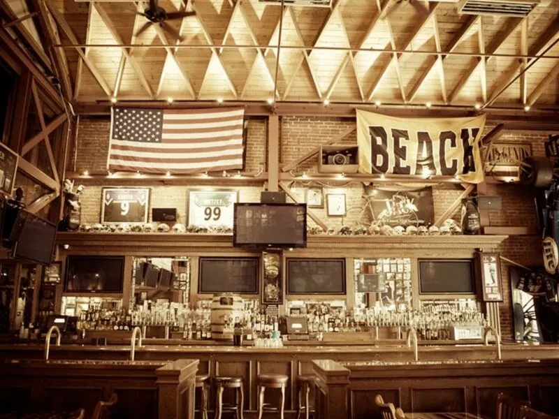 Rustic pub interior featuring a long wooden bar and sports memorabilia.