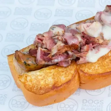 Toasted bun sausage with sliced meat, bacon, and melted cheese.