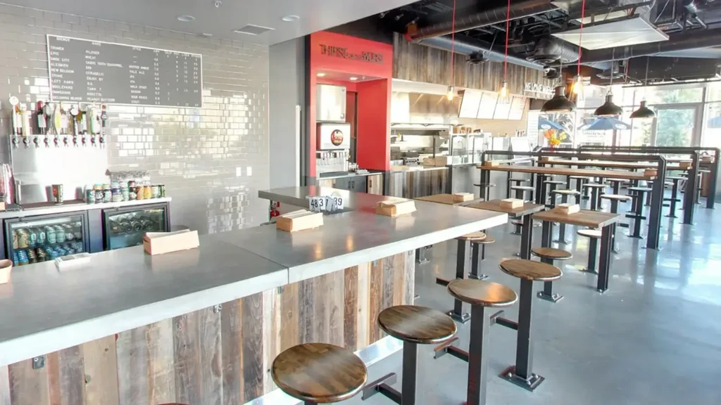 Modern industrial-chic restaurant interior with bar, menu, and dining area.