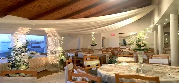 Elegant event hall with floral centerpieces, fabric canopy, and water view.