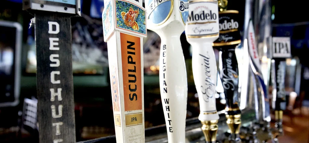 Close-up of various beer tap handles, including Sculpin and Modelo.