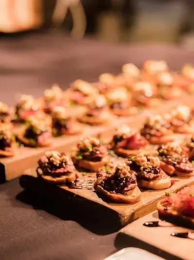 Close-up: Meat canapés with sauce and nuts on rustic wooden boards.