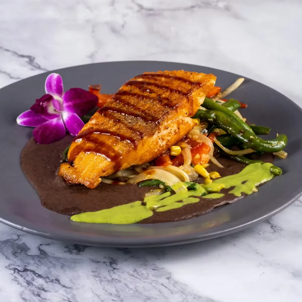 Glazed salmon, colorful vegetables, two sauces, and an orchid garnish.