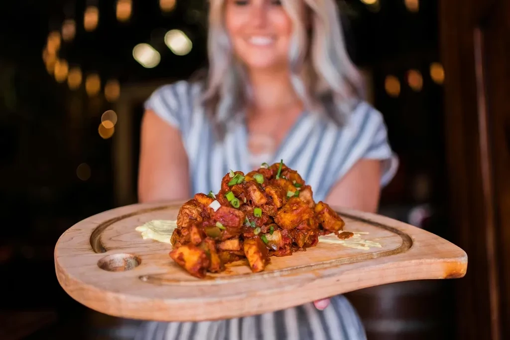 Food with red sauce and green onions on a rustic serving board.