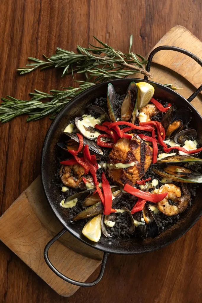 Black rice seafood paella with shrimp, mussels, and lemon.