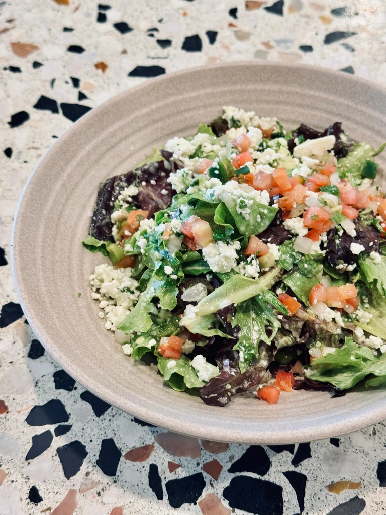 Vibrant salad with mixed greens, feta, and tomatoes in a bowl.