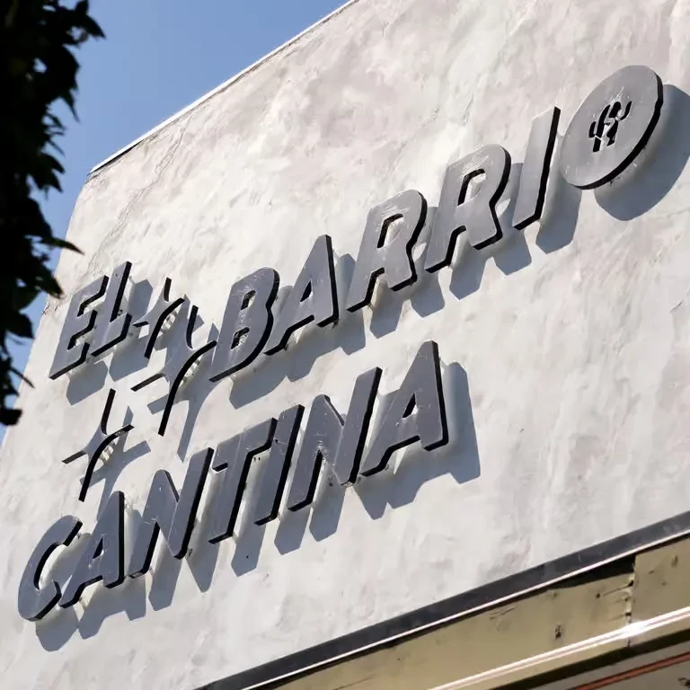 EL BARRIO CANTINA sign with dark raised letters on a light textured wall.